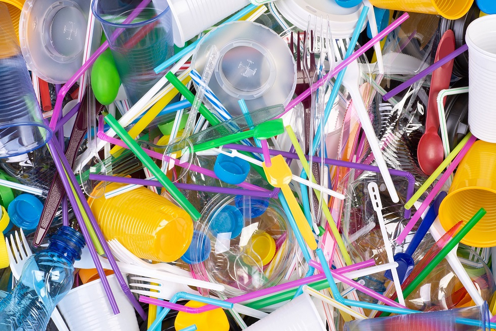 A collection of single-use plastics, including plastic forks, colourful straws, and to-go lids and cups